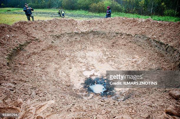 People walk around a crater near the northern Latvian town of Mazsalaca on October 26, 2009. A telephone company on October 26 said it had dreamed up...