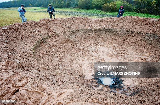 People walk around a crater near the northern Latvian town of Mazsalaca on October 26, 2009. A telephone company on October 26 said it had dreamed up...