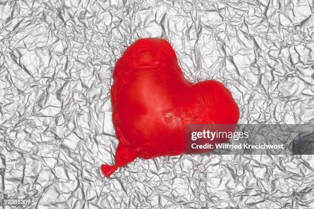 shrinking heart balloon on silver background - foil balloon stock pictures, royalty-free photos & images