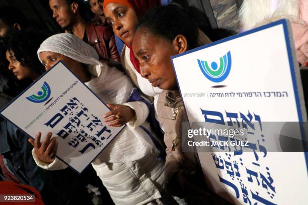 African migrants hold signs bearing Hebrew text of an extract from Exodus 23:9 from the Bible: "thou shalt not oppress a stranger: for ye know the...