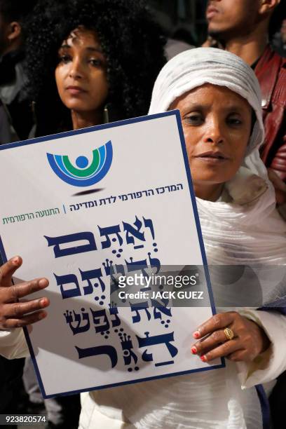 An African migrant holds a sign reading in Hebrew "You come from the Bible, you too are refugees", during a demonstration in the Israeli coastal city...