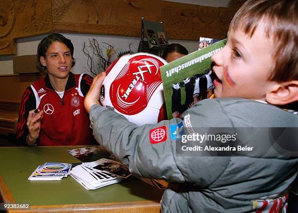 Defender Annike Krahn of the women's German national soccer team hands over a soccer ball after she signed an autograph on it during her visit at an...