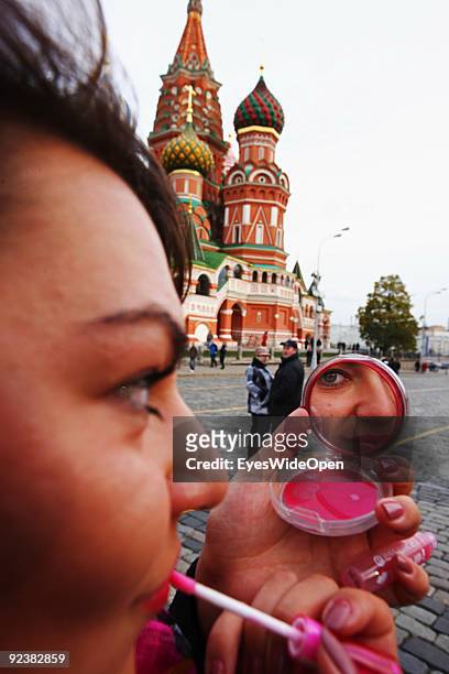 Woman is styling herself with lipstick in front of the Cathedral of Saint Basil on the Red Square on October 14, 2009 in Moscow, Russia. The russian...