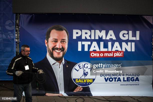 Contractor gathers cables as a banner displaying Matteo Salvini, leader of the euroskeptic party League, hangs after an election campaign rally at...