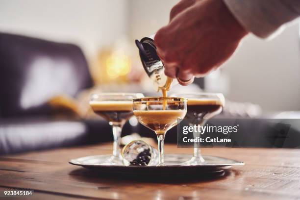 männliche hände gießen espresso martini cocktail in glas - likör stock-fotos und bilder