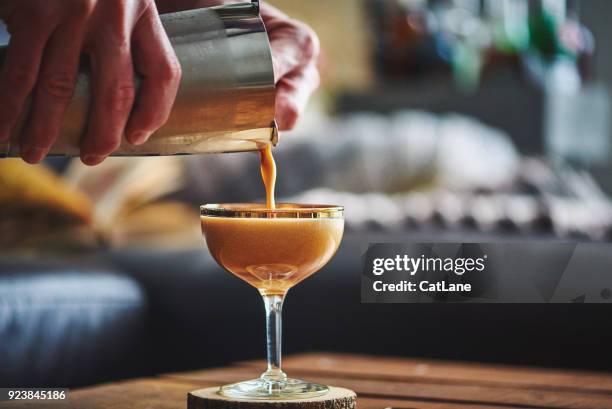 mannelijke handen gieten espresso martini cocktail in glas - martini stockfoto's en -beelden
