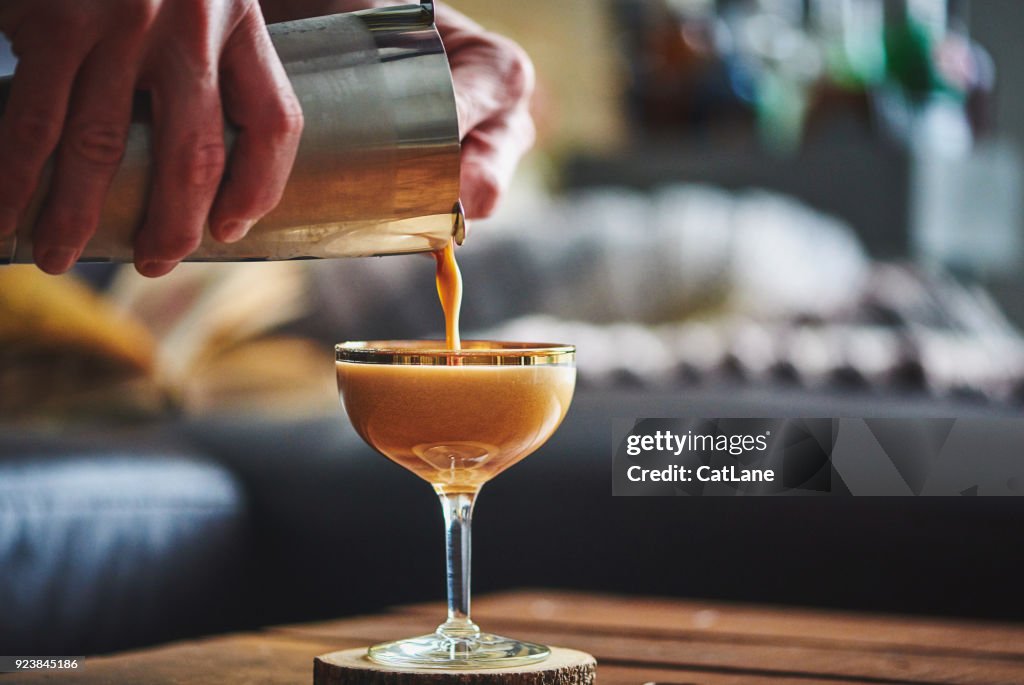 Male hands pouring espresso martini cocktail into glass