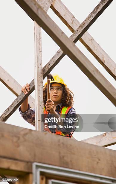 woman hammering in nails on a wooden house frame - senneville stock pictures, royalty-free photos & images