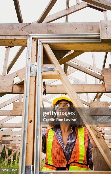 woman hammering in nails on a wooden house frame - senneville stock pictures, royalty-free photos & images