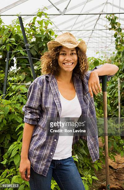 young woman leaning on a rake in a greenhouse - senneville stock pictures, royalty-free photos & images