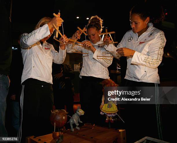 Players Jennifer Zietz , Celia Okoyino da Mbabi and Kim Kulig of the women's German national team play with marionettes during their visit at the...