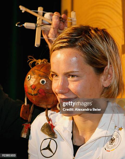 Player Jennifer Zietz of the women's German national soccer team smiles as she poses with a soccer ball marionette during her visit at the...