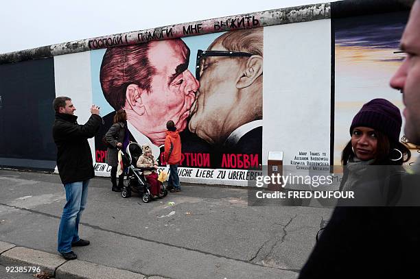 Tourists look at a preserved segment of the Berlin wall at East Side Gallery on Berlin's Muhlen Strasse on October 25, 2009. Germany will celebrate...