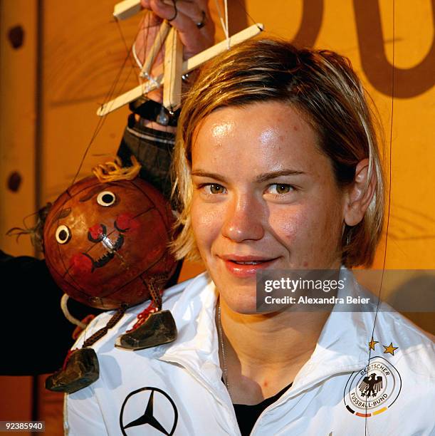 Player Jennifer Zietz of the women's German national soccer team smiles as she poses with a soccer ball marionette during her visit at the...