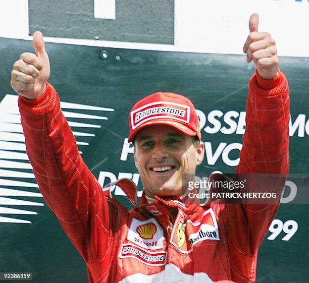 Northern Ireland's Ferrari driver Eddie Irvine holds his trophy on the podium after winning the Formula One Grand Prix of Germany, 01 August 1999 on...