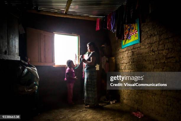 young woman weaving bracelets by window. - guatemala family stock pictures, royalty-free photos & images