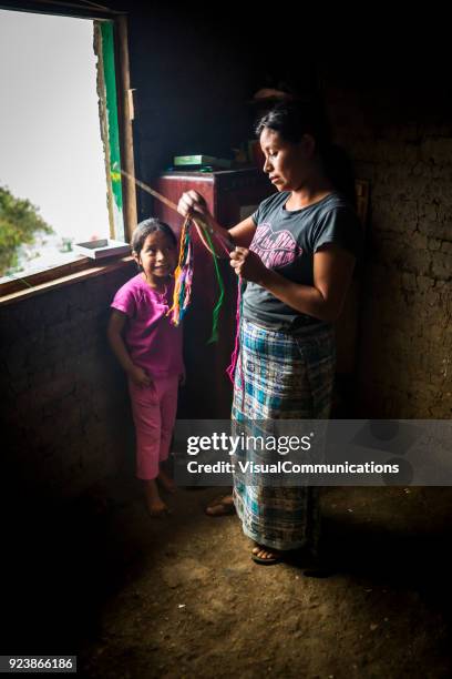 young woman weaving bracelets by window. - guatemala family stock pictures, royalty-free photos & images