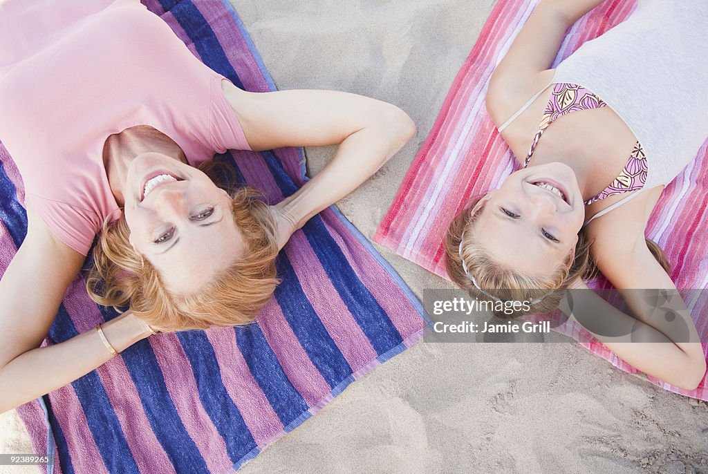 Mother and daughter lying on beach together