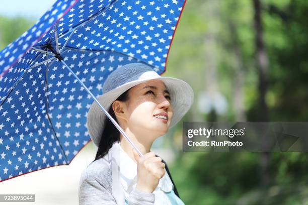 middle aged woman holding parasol outdoors - sombrilla fotografías e imágenes de stock