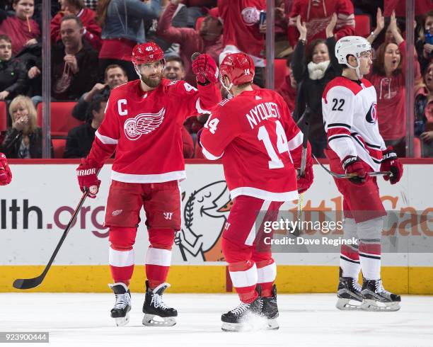 Henrik Zetterberg of the Detroit Red Wings celebrates his second period goal with teammate Gustav Nyquist as Brett Pesce of the Carolina Hurricanes...