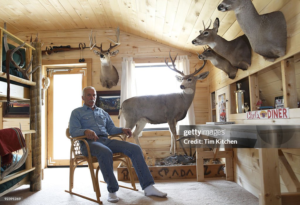Man sitting in sunlit cabin with taxidermy