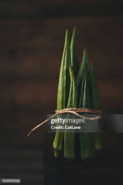 stillleben mit gebündelten okra in dunklen stimmungsvolle licht gedreht - okra stock-fotos und bilder