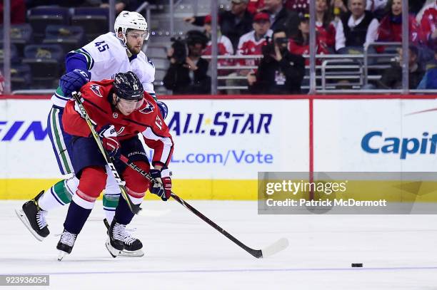 Jakub Vrana of the Washington Capitals and Michael Chaput of the Vancouver Canucks battle for the puck in the first period at Capital One Arena on...