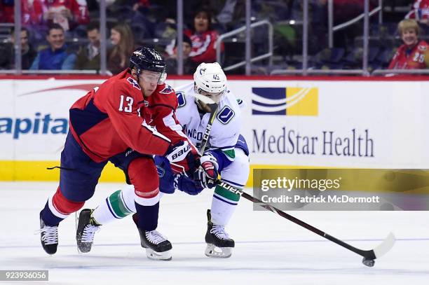 Jakub Vrana of the Washington Capitals and Michael Chaput of the Vancouver Canucks battle for the puck in the first period at Capital One Arena on...