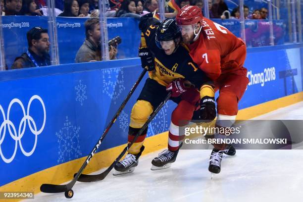 Germany's Christian Ehrhoff and Russia's Ivan Telegin fight for the puck in the men's gold medal ice hockey match between the Olympic Athletes from...