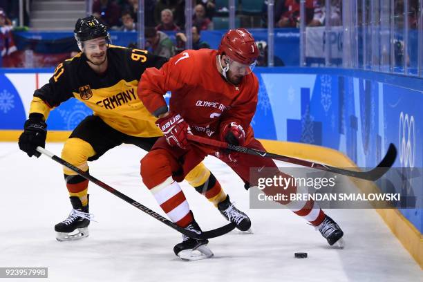 Germany's Moritz Muller and Russia's Ivan Telegin fight for the puck in the men's gold medal ice hockey match between the Olympic Athletes from...