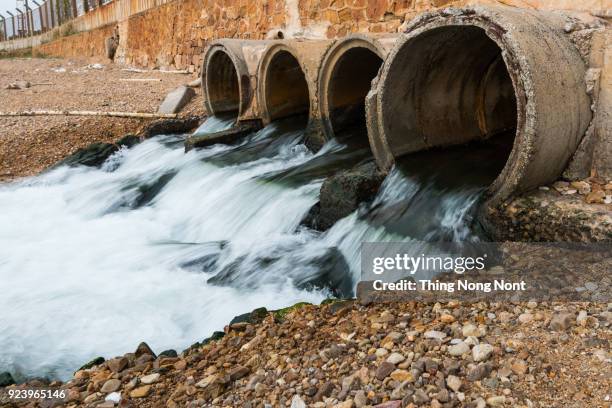 water flowing from sewage pipe - burst pipe stockfoto's en -beelden