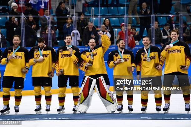 The Germany team poses with their silver medals after the medal ceremony after the men's gold medal ice hockey match between the Olympic Athletes...