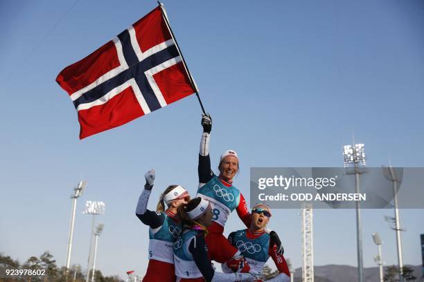 Norway's Marit Bjoergen is lifted by her compatriots as she waves the Norwegian flag after winning gold in the women's 30km cross country mass start...