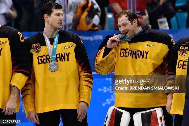 Germany's Danny aus den Birken bites his silver medal on the podium during the medal ceremony after the men's gold medal ice hockey match between the...