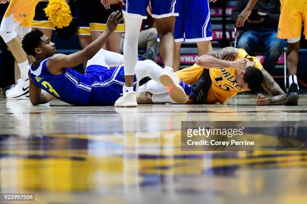 Anthony Mosley of the Delaware Fightin Blue Hens is helped up after being fouled by Sammy Mojica of the Drexel Dragons who reacts to the call during...