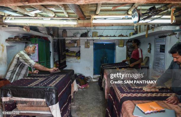 This picture taken on February 23, 2018 shows Indian artisans making traditional Ajrakh block printing designs on bedsheets at a workshop at Khavda...