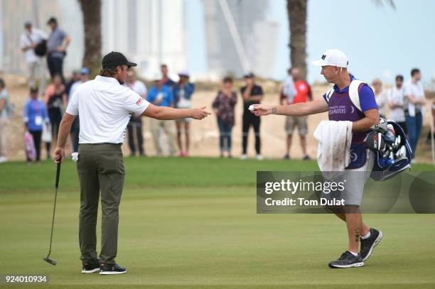 Eddie Pepperell of England is handed his ball by caddie Mick Doran on the 16th green during the final round of the Commercial Bank Qatar Masters at...