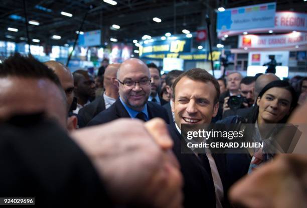 French President Emmanuel Macron winks as he shakes hands during the 55th International Agriculture Fair at the Porte de Versailles exhibition center...