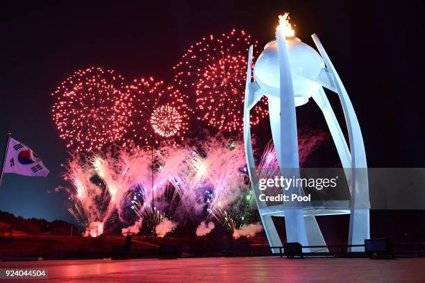 Fireworks explode behind the Olympic flame during the Closing Ceremony of the PyeongChang 2018 Winter Olympic Games at PyeongChang Olympic Stadium on...