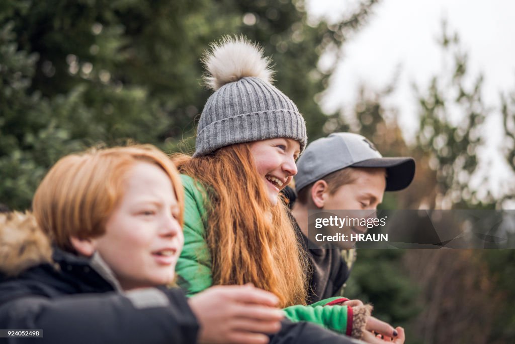 Smiling girl with brothers relaxing in forest