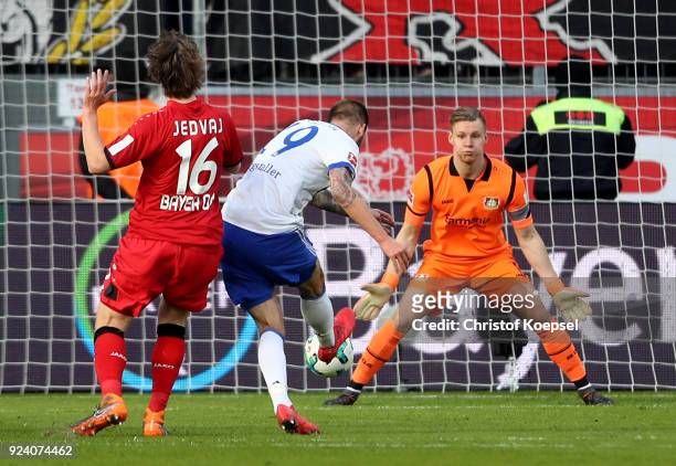 Guido Burgstaller of Schalke scores the first goal against Tin Jedvaj and Bernd Leno of Leverkusen during the Bundesliga match between Bayer 04...