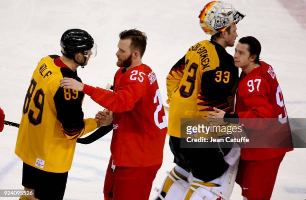 Mikhail Grigorenko and Nikita Gusev of OAR cheer David Wolf and Danny Aus Den Birken of Germany following the Men's Ice Hockey Gold Medal match...