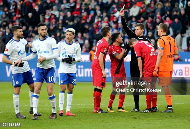Referee Daniel Siebert 3rd R) shows Panagiotis Retsos of Leverkusen t the yellow card and decides for penalty during the Bundesliga match between...