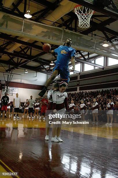 Troy McCray of Team Flight Brothers dunks over two Lynn English High School cheer leaders at Lynn English High School Gymnasium on October 27, 2009...