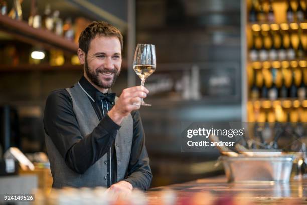 handsome sommelier tasting wine at a wine cellar looking very happy - bar drink establishment stock pictures, royalty-free photos & images