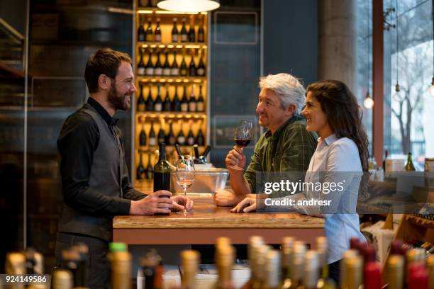 couple at a winery wine tasting with the help of a handsome sommelier - bar drink establishment stock pictures, royalty-free photos & images