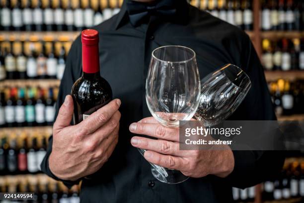 unrecognizable man holding glasswines and a wine bottle at a restaurant - bar drink establishment stock pictures, royalty-free photos & images