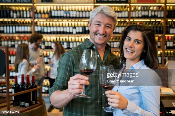 couple on a date at a winery tasting red wine and looking at camera smiling very happy - bar drink establishment stock pictures, royalty-free photos & images