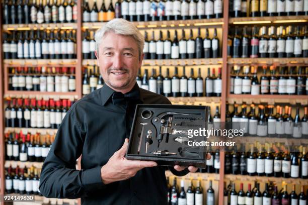 happy salesman showing a box with wine accesories - bar drink establishment stock pictures, royalty-free photos & images