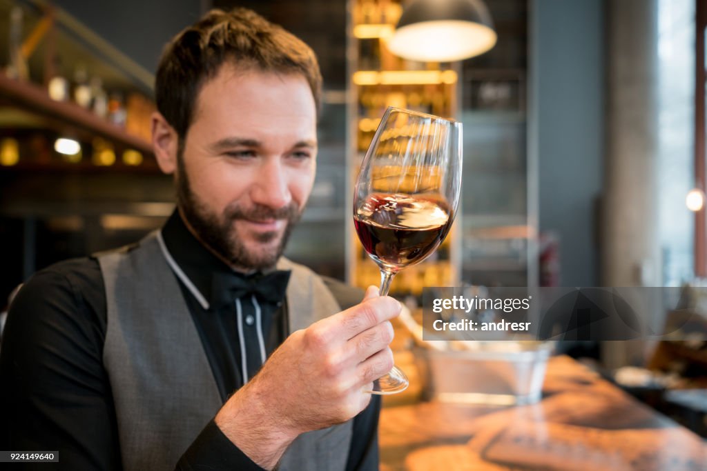 Professional wine taster at a wine cellar looking at the color of the wine smiling